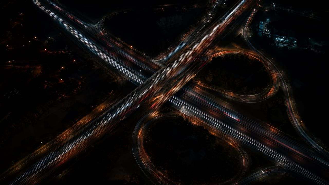 Aerial night view of a highway interchange traced by vehicle light trails